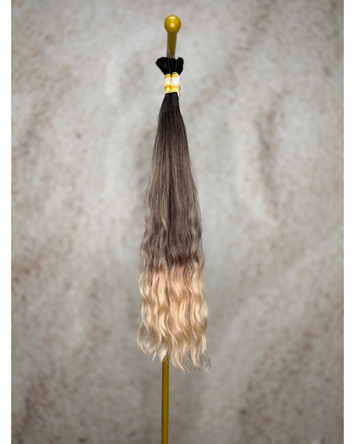 Four bundles of golden blond ombre body wavy bulk hair arranged together.