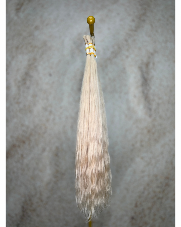 Four bundles of light blond body wavy bulk hair arranged together.