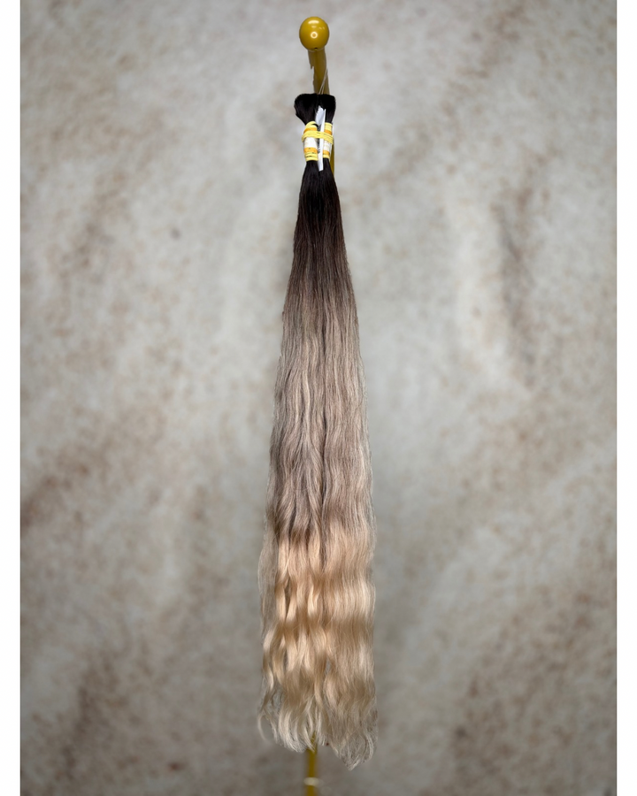 Four bundles of medium blond balayage body wavy bulk hair arranged together.